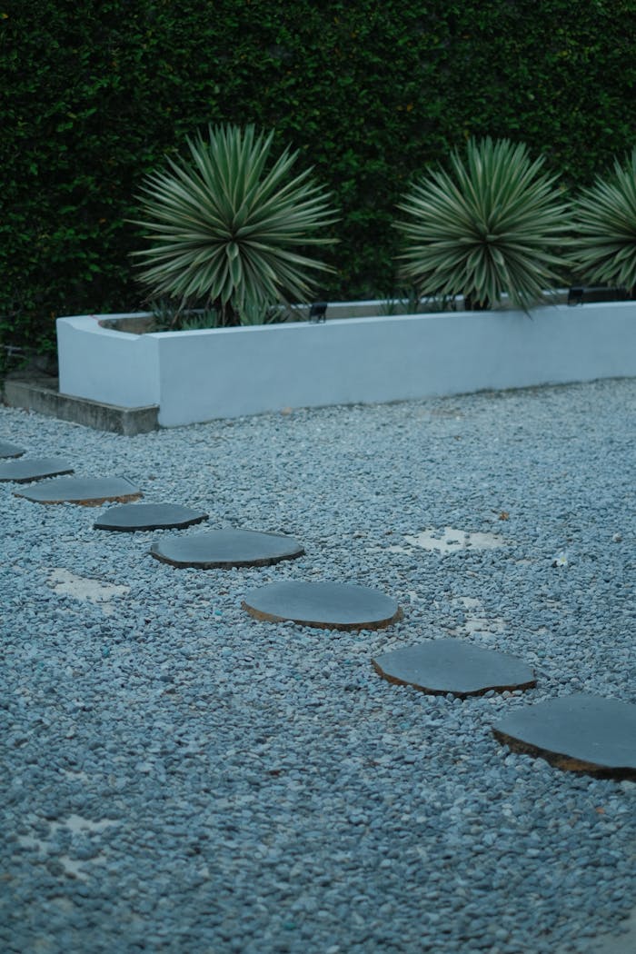 Circular stone pathway in a modern garden with agave plants and gravel.